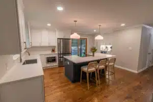 An upgraded kitchen with white cabinets and a blue accented island and white countertops.