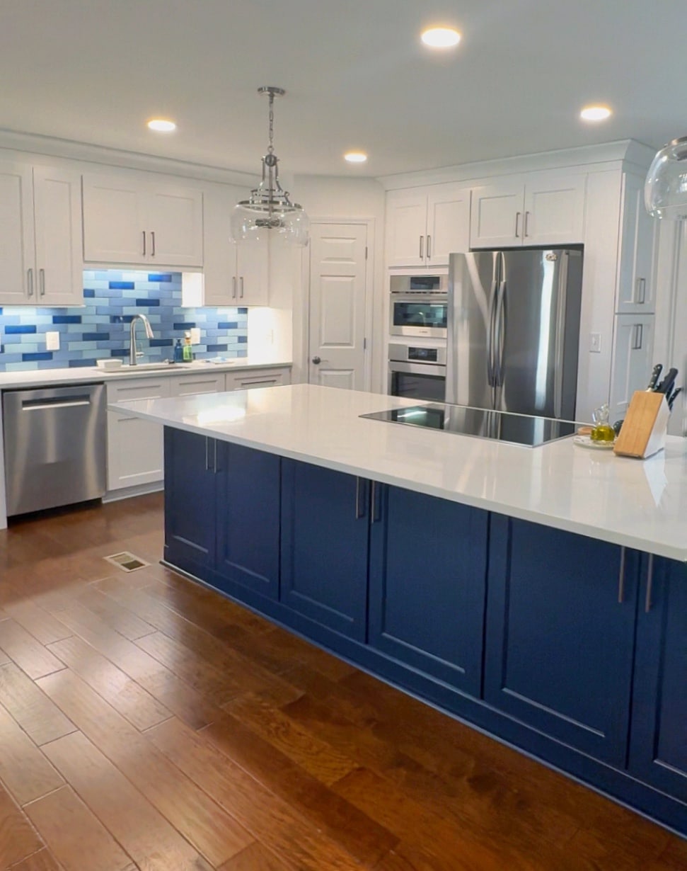 Kitchen remodel with a tiled backsplash in various shades of blue and dark blue cabinets under the island